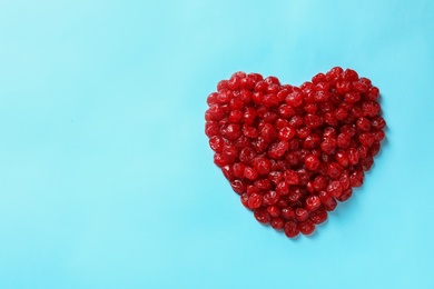 Photo of Heart shaped heap of sweet cherries on color background, top view with space for text. Dried fruit as healthy snack