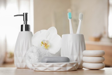 Image of Bath accessories. Different personal care products and flower on wooden table in bathroom