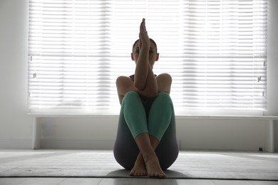 Photo of Woman practicing eagle asana in yoga studio. Garudasana pose