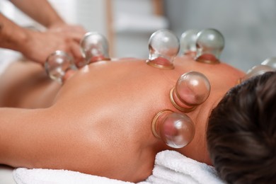 Photo of Therapist giving cupping treatment to patient on massage couch in spa salon, closeup