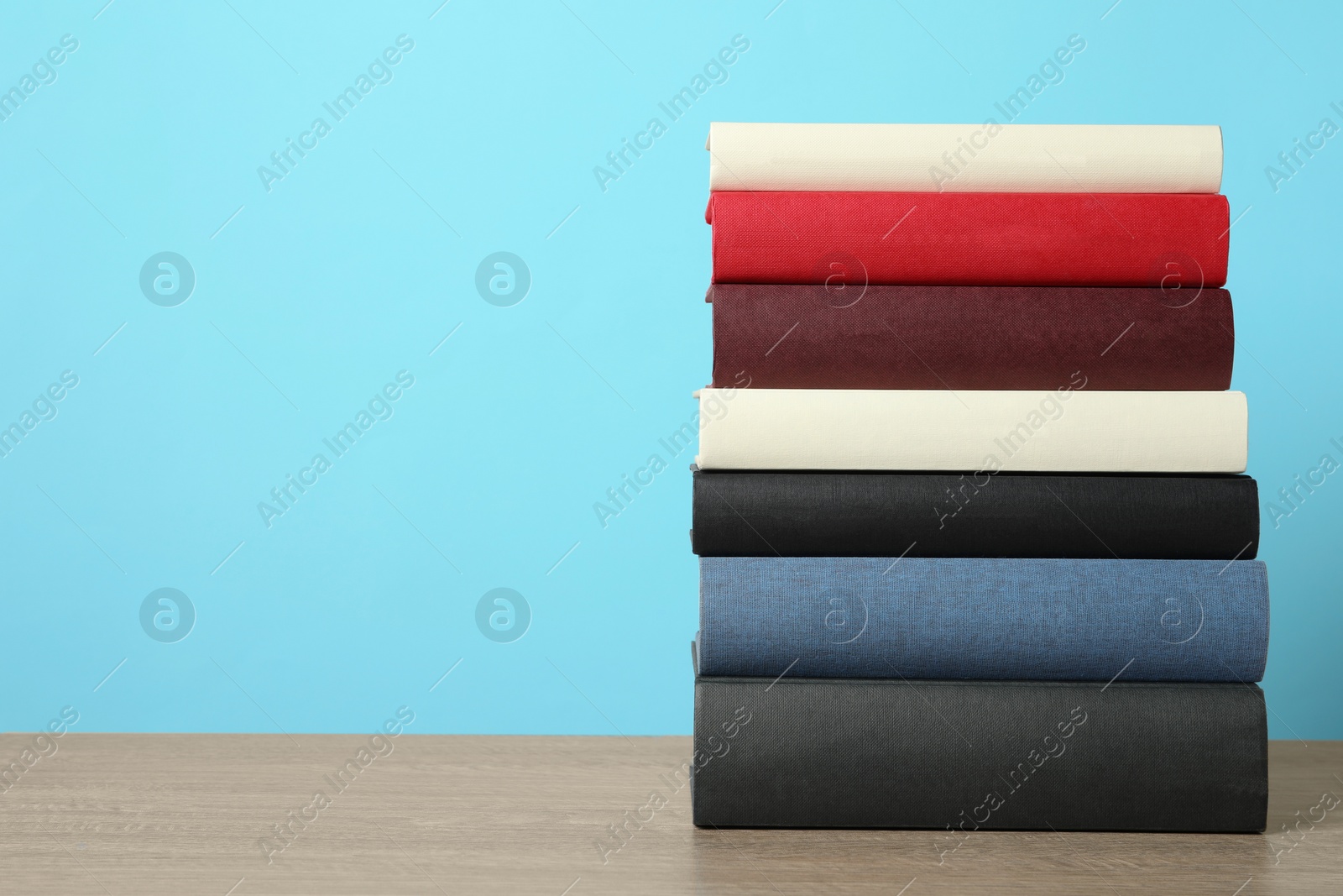 Photo of Stack of hardcover books on wooden table, space for text