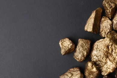 Photo of Pile of gold nuggets on dark background, flat lay with space for text