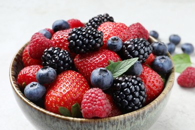 Different fresh ripe berries in bowl on table, closeup