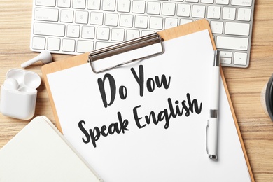 Photo of Clipboard with question Do You Speak English and stationery on wooden table, flat lay