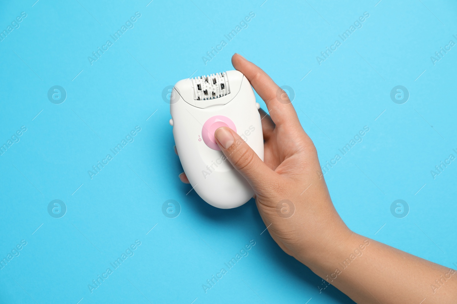 Photo of Woman holding modern epilator on light blue background, top view