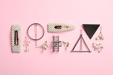 Photo of Stylish hair clips and flowers on pink background, flat lay