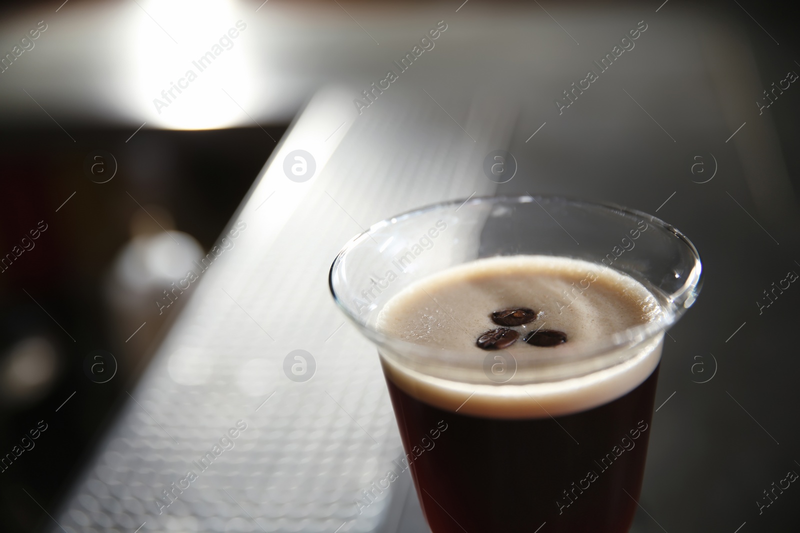 Photo of Glass of martini espresso cocktail in bar, closeup. Space for text