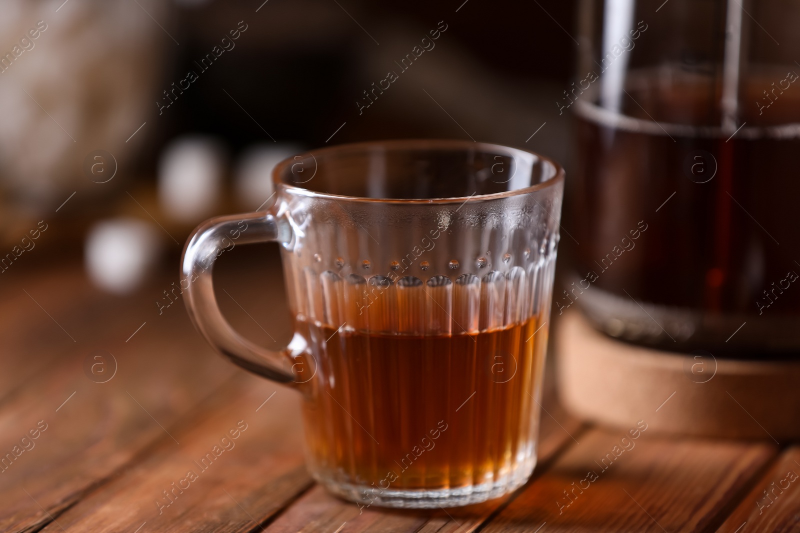 Photo of Glass cup with delicious tea on wooden table, closeup