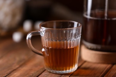 Photo of Glass cup with delicious tea on wooden table, closeup