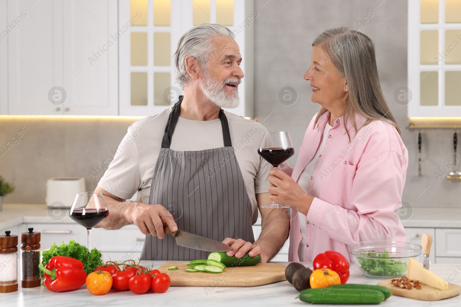 Photo of Affectionate senior couple cooking together in kitchen