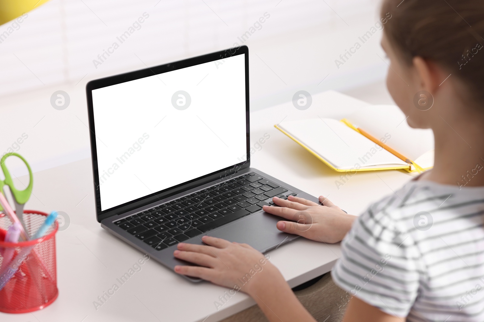 Photo of E-learning. Girl using laptop during online lesson at table indoors, closeup