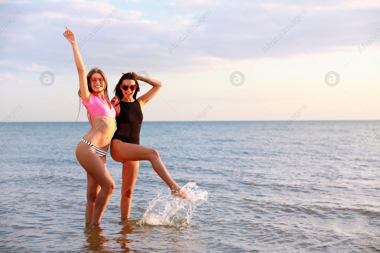 Photo of Young woman in bikini with girlfriend on beach. Lovely couple