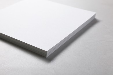 Blank paper sheets on grey textured table, closeup. Mockup for design