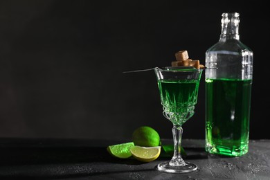 Photo of Absinthe, brown sugar and lime on black table, space for text. Alcoholic drink