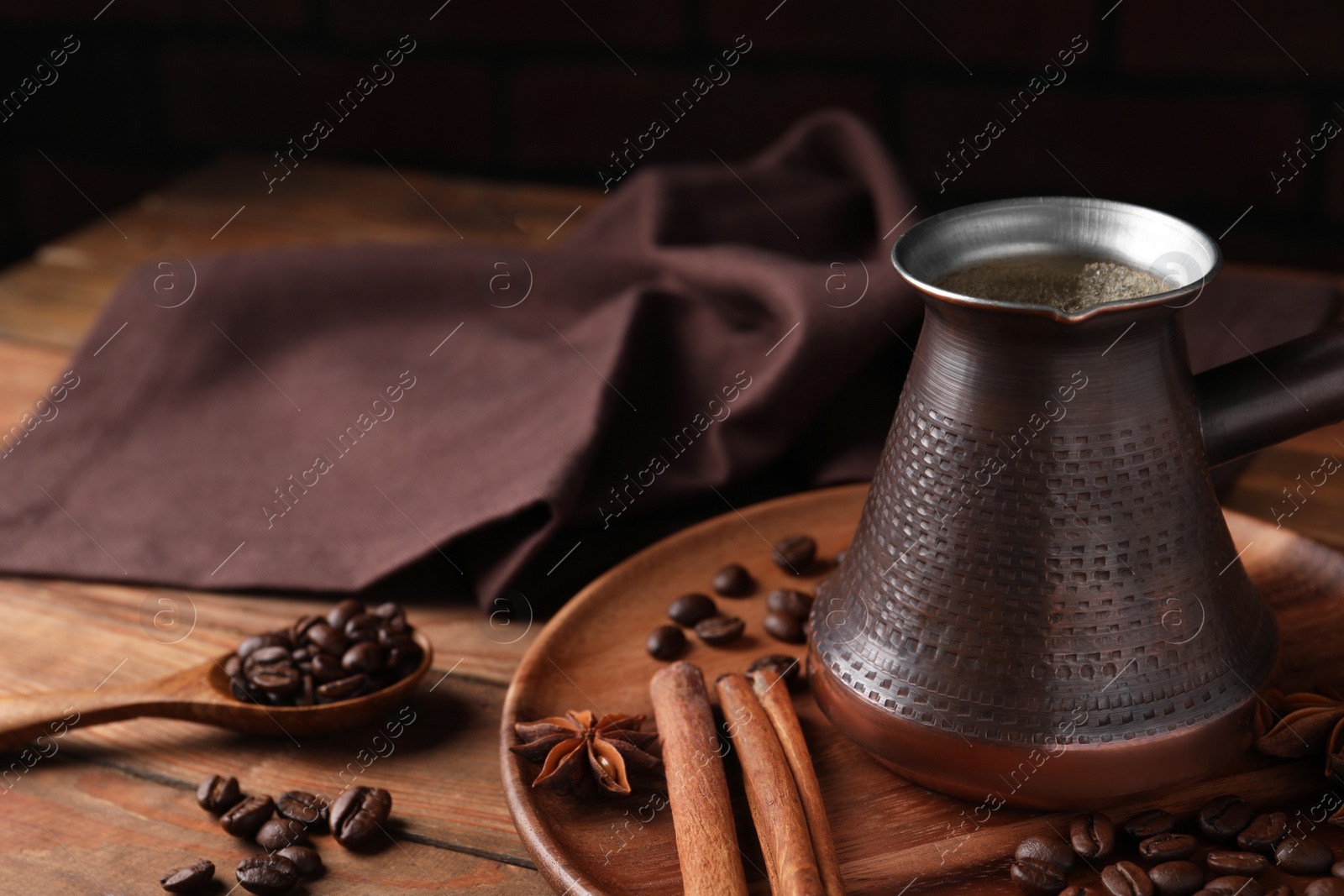 Photo of Cezve with Turkish coffee, beans and spices on wooden table, space for text