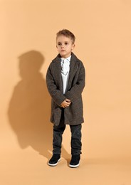 Photo of Fashion concept. Stylish boy posing on pale orange background