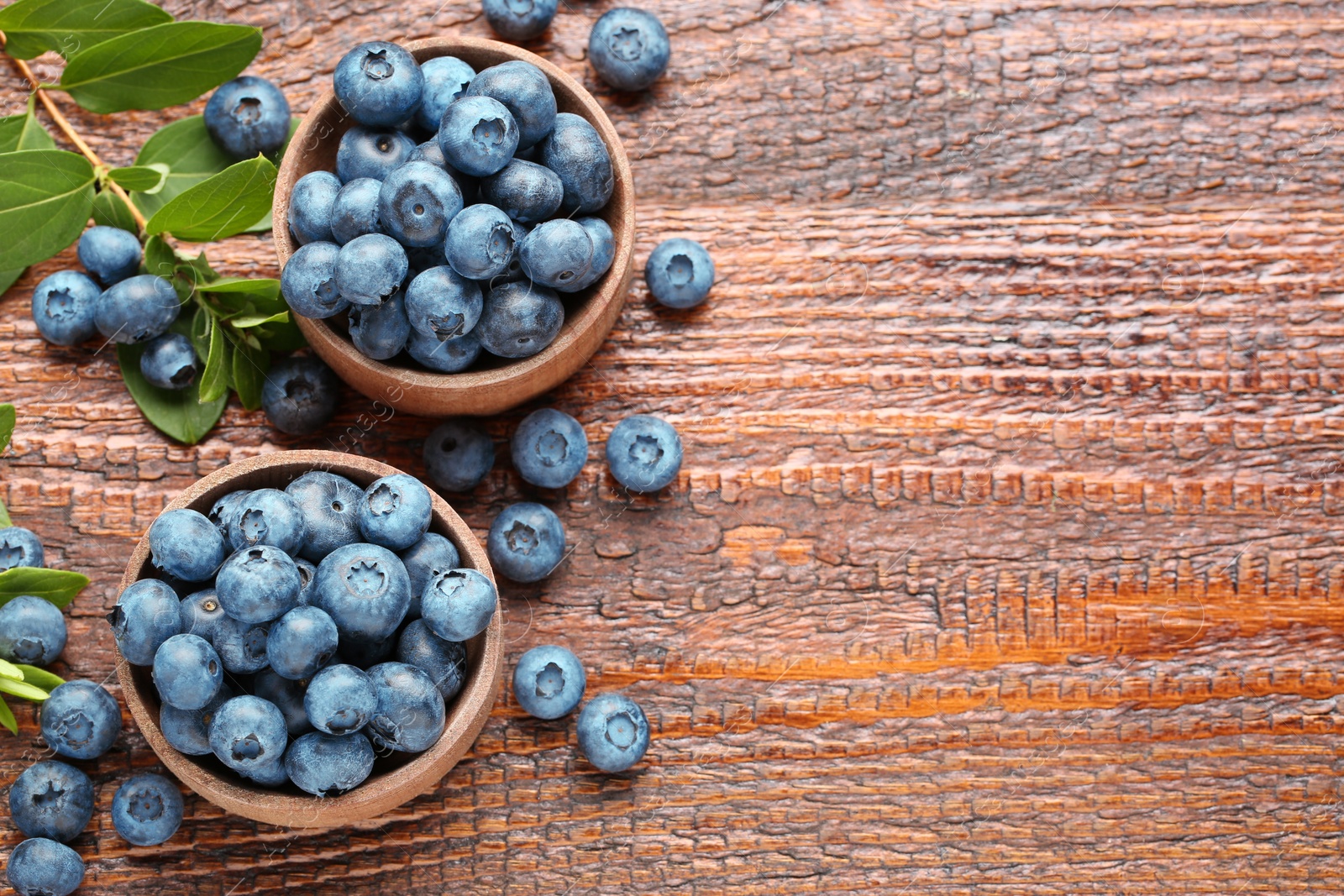 Photo of Tasty fresh blueberries on wooden table, flat lay. Space for text