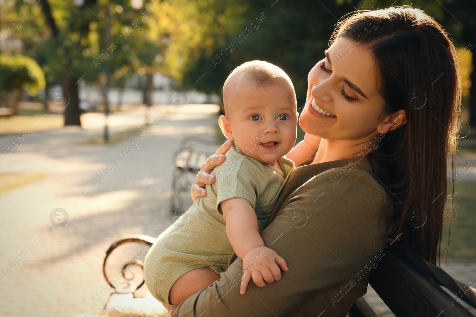 Photo of Young mother with her cute baby on bench in park