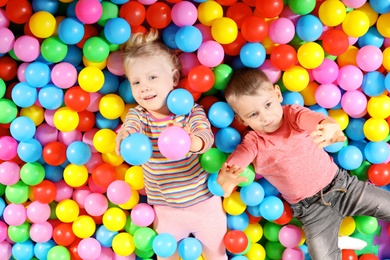 Cute children playing in ball pit indoors, top view