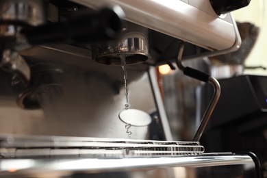 Photo of Water pouring from modern coffee machine, closeup