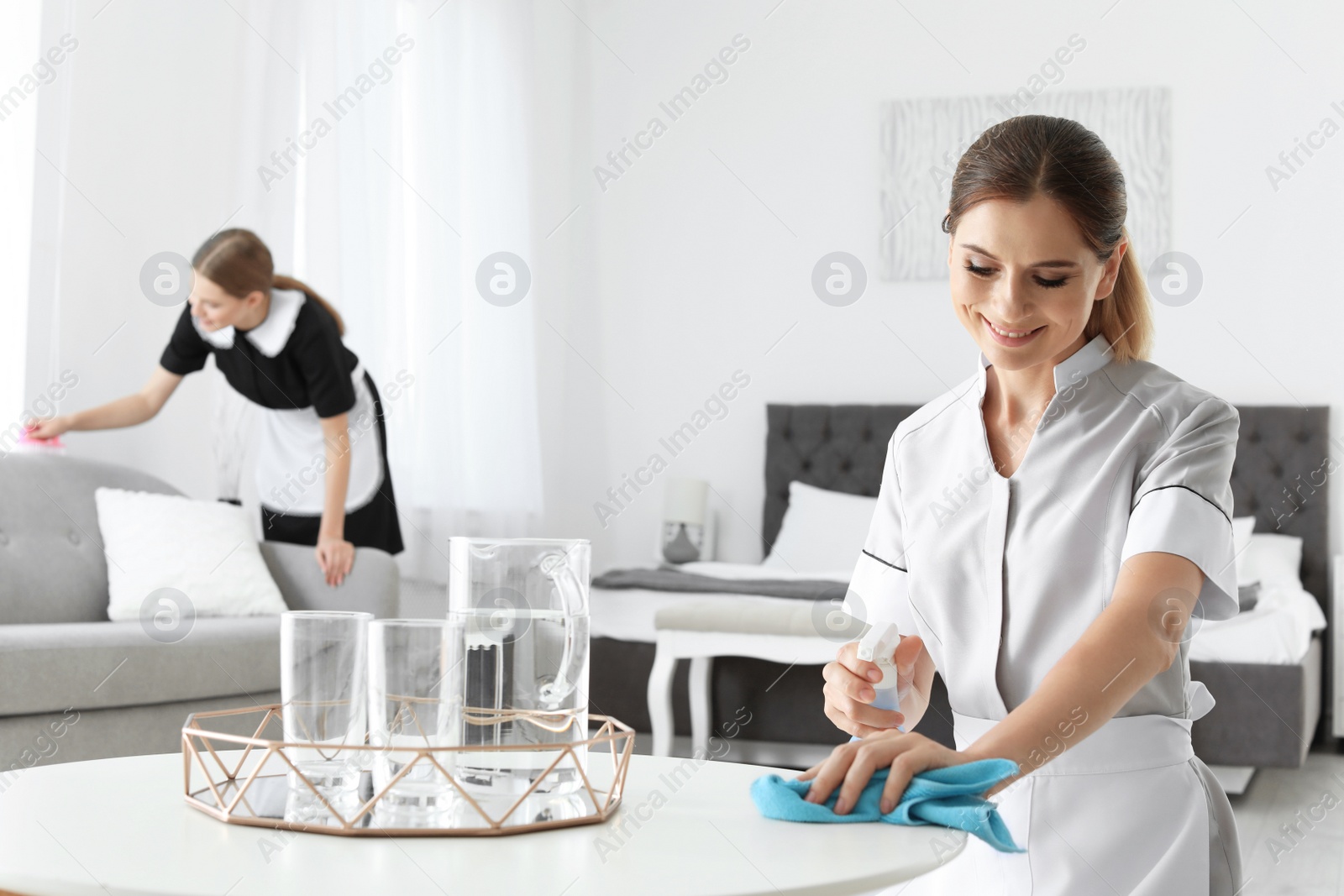 Photo of Professional chambermaid cleaning table in hotel room