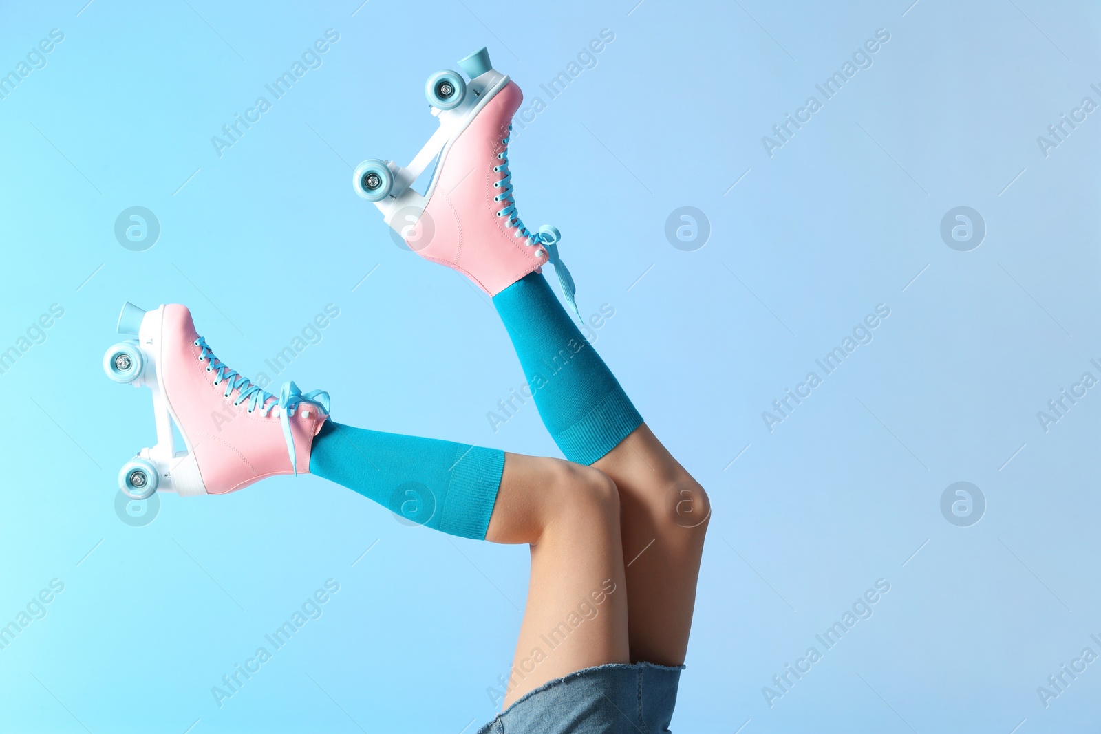 Photo of Woman with vintage roller skates on color background, closeup. Space for text