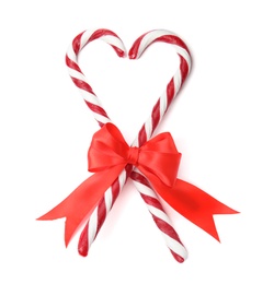 Photo of Heart shape made of tasty candy canes with bow on white background