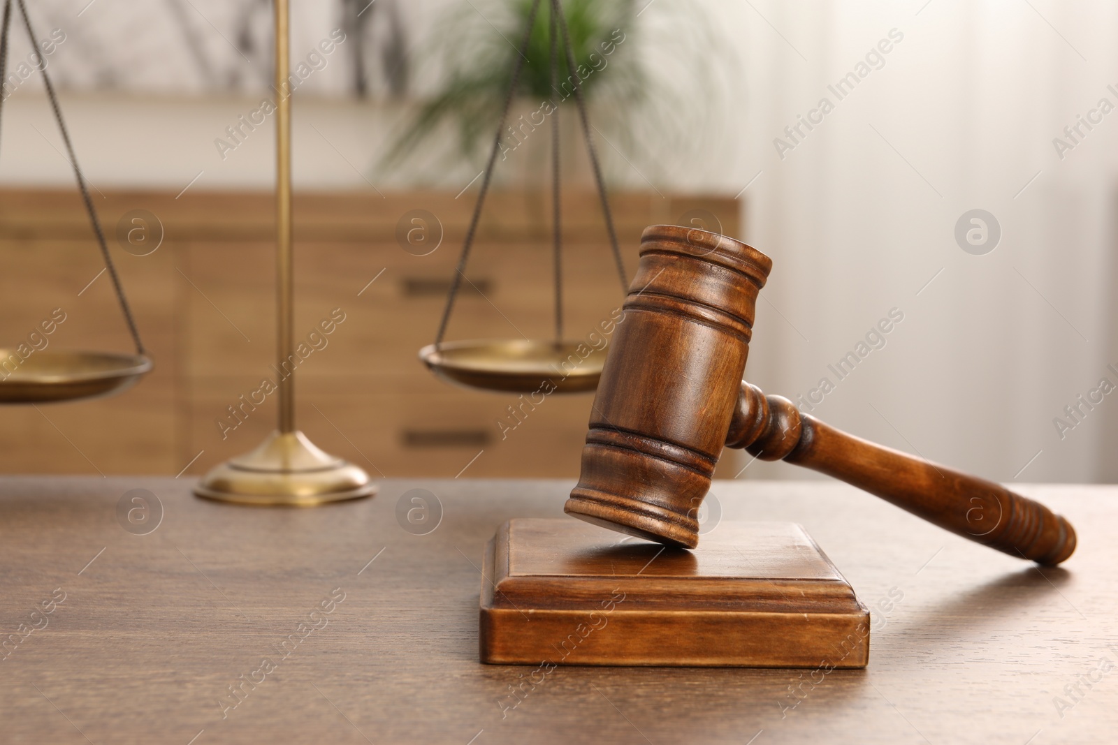 Photo of Wooden gavel, sound block and scales on table indoors, closeup. Space for text