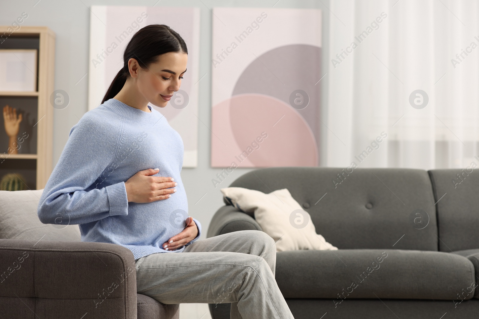 Photo of Pregnant young woman on armchair at home, space for text