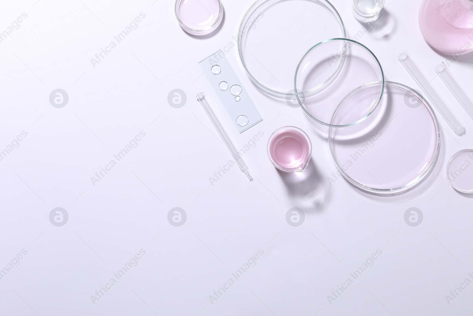 Photo of Organic cosmetic product and laboratory glassware on white background, top view. Space for text