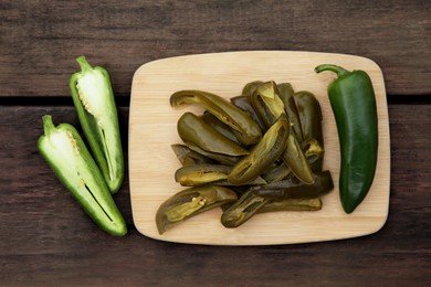 Fresh and pickled green jalapeno peppers on wooden table, flat lay