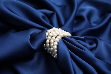 Beautiful pearls with dark blue silk as background, closeup