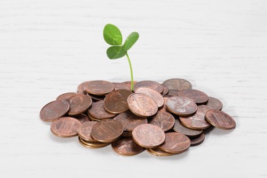 Photo of Coins with green sprout on white wooden table, closeup. Investment concept