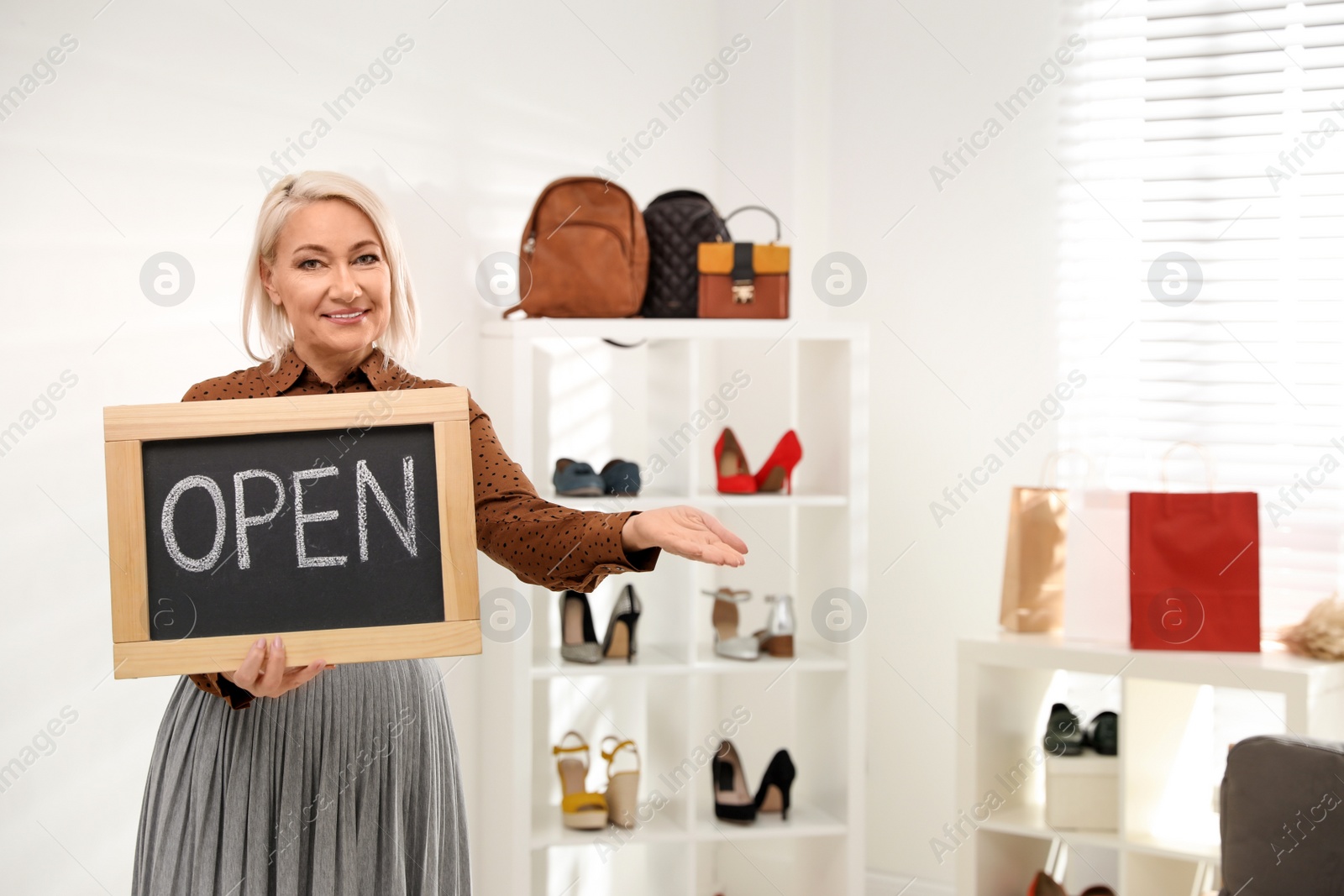 Photo of Female business owner holding OPEN sign in boutique. Space for text