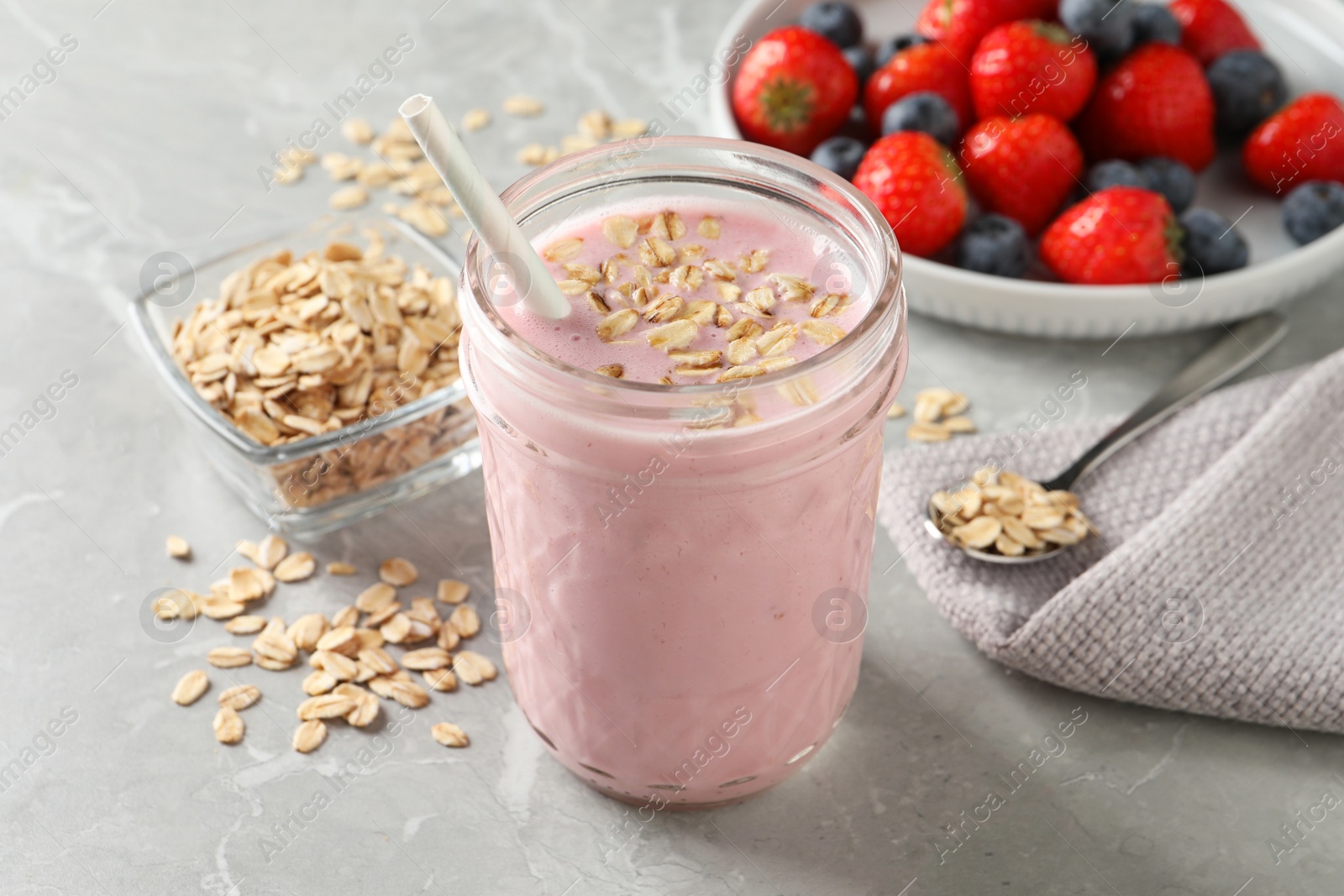 Photo of Jar of tasty berry oatmeal smoothie on grey table