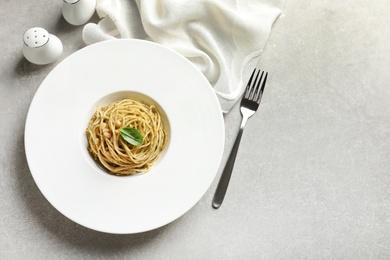 Photo of Plate of delicious basil pesto pasta served for dinner on table, flat lay with space for text