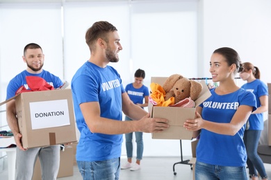 Young volunteers holding boxes with donations indoors