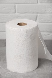 Photo of Roll of white paper towels on grey table near brick wall