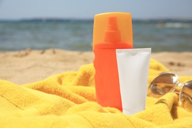 Photo of Sunscreen, sunglasses and towel on sandy beach, space for text. Sun protection care