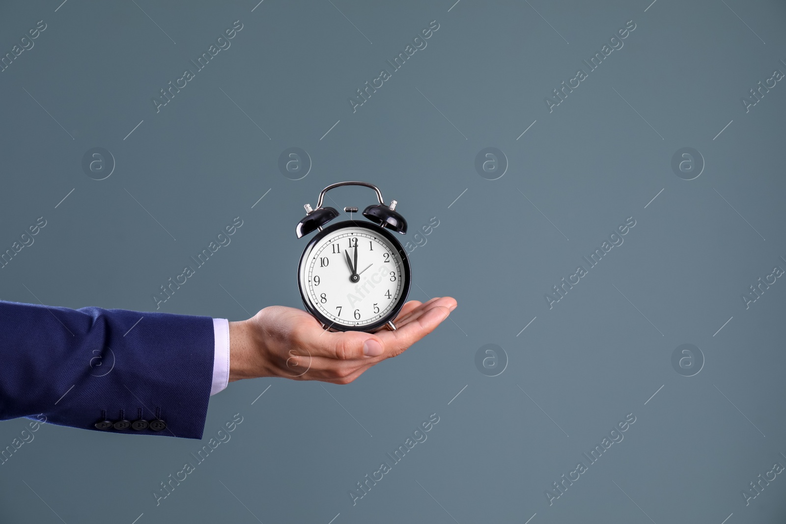 Photo of Young businessman holding clock on color background. Time management