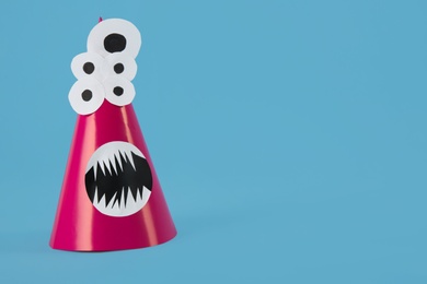Photo of Funny pink monster on light blue background, space for text. Halloween decoration
