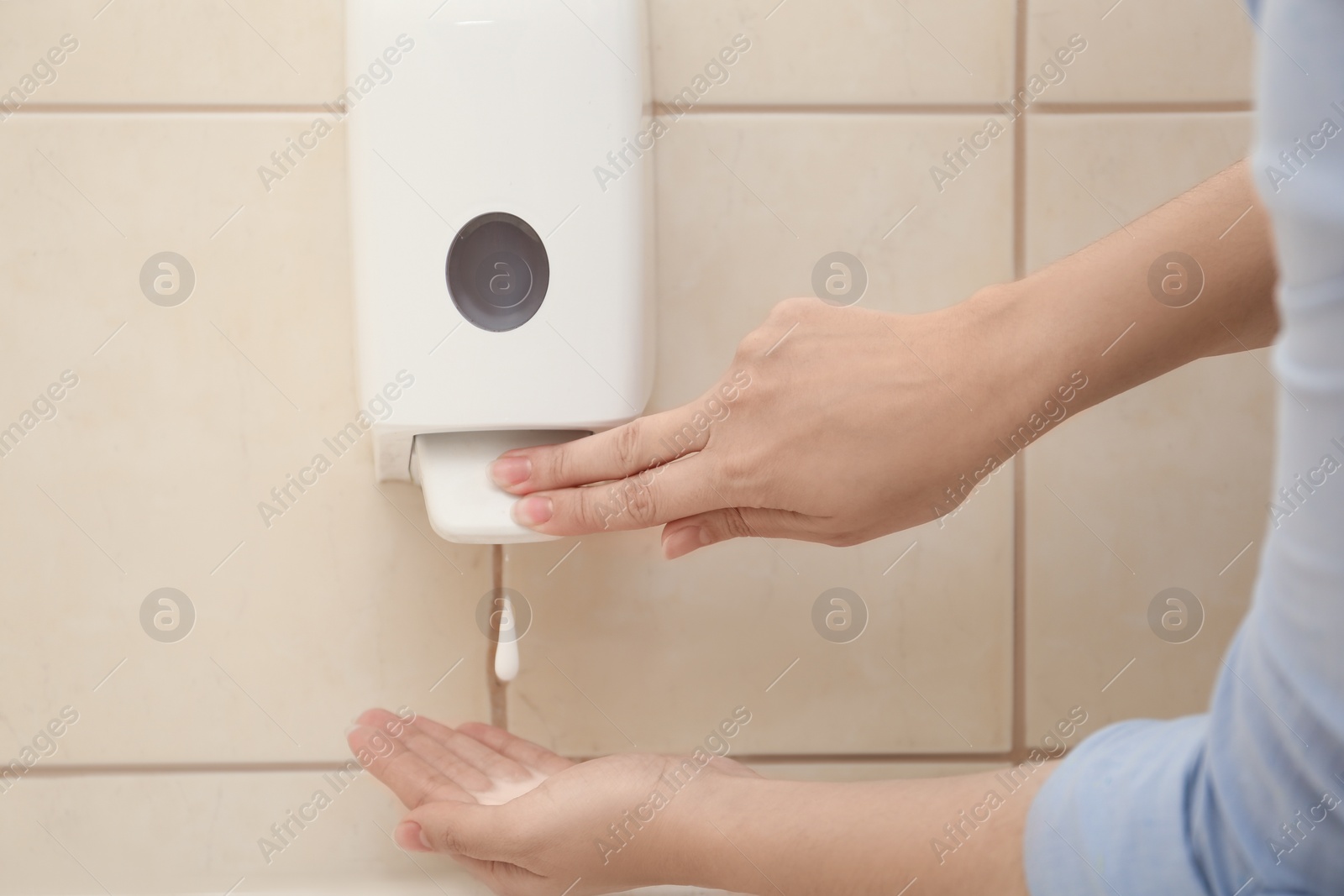 Photo of Woman applying antiseptic soap onto hand in bathroom, closeup. Virus prevention