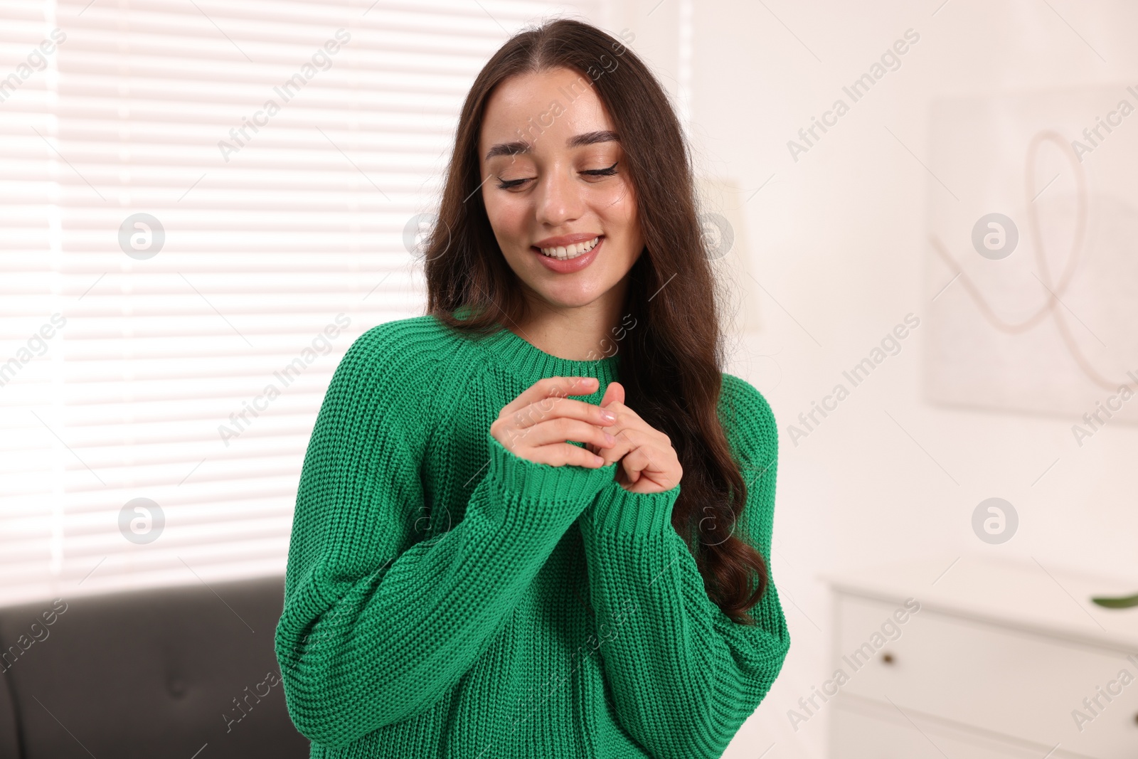 Photo of Beautiful young woman in stylish warm sweater at home