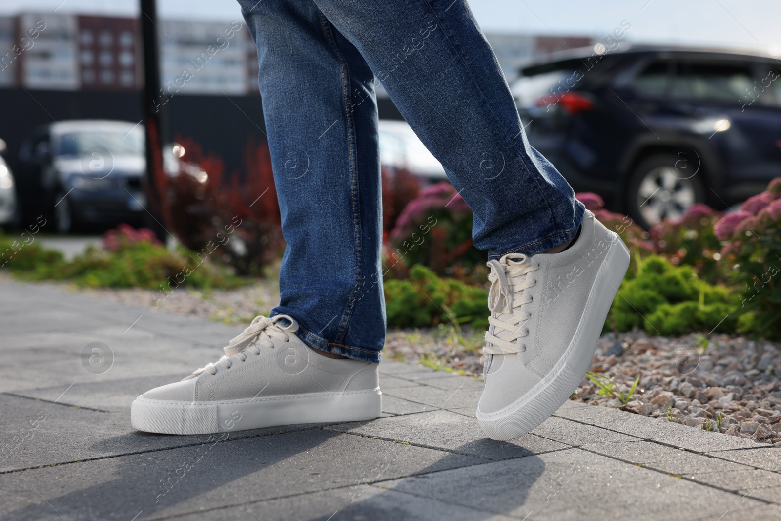 Photo of Man wearing pair of stylish sneakers outdoors, closeup