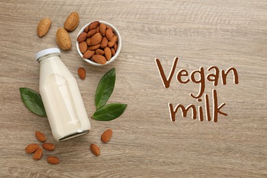 Image of Delicious vegan almond milk and nuts on wooden table, flat lay