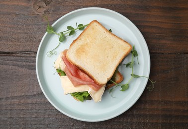 Photo of Tasty sandwich with brie cheese and prosciutto on wooden table, top view