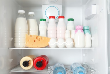 Photo of Open refrigerator with many different products, closeup