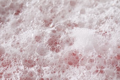 White washing foam on pale pink background, closeup