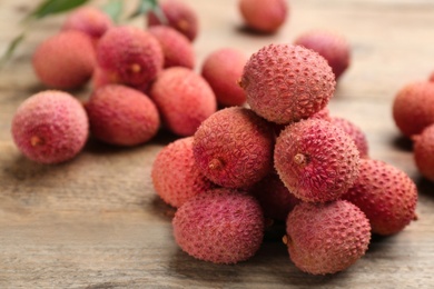 Photo of Fresh ripe lychees on wooden table, closeup. space for text