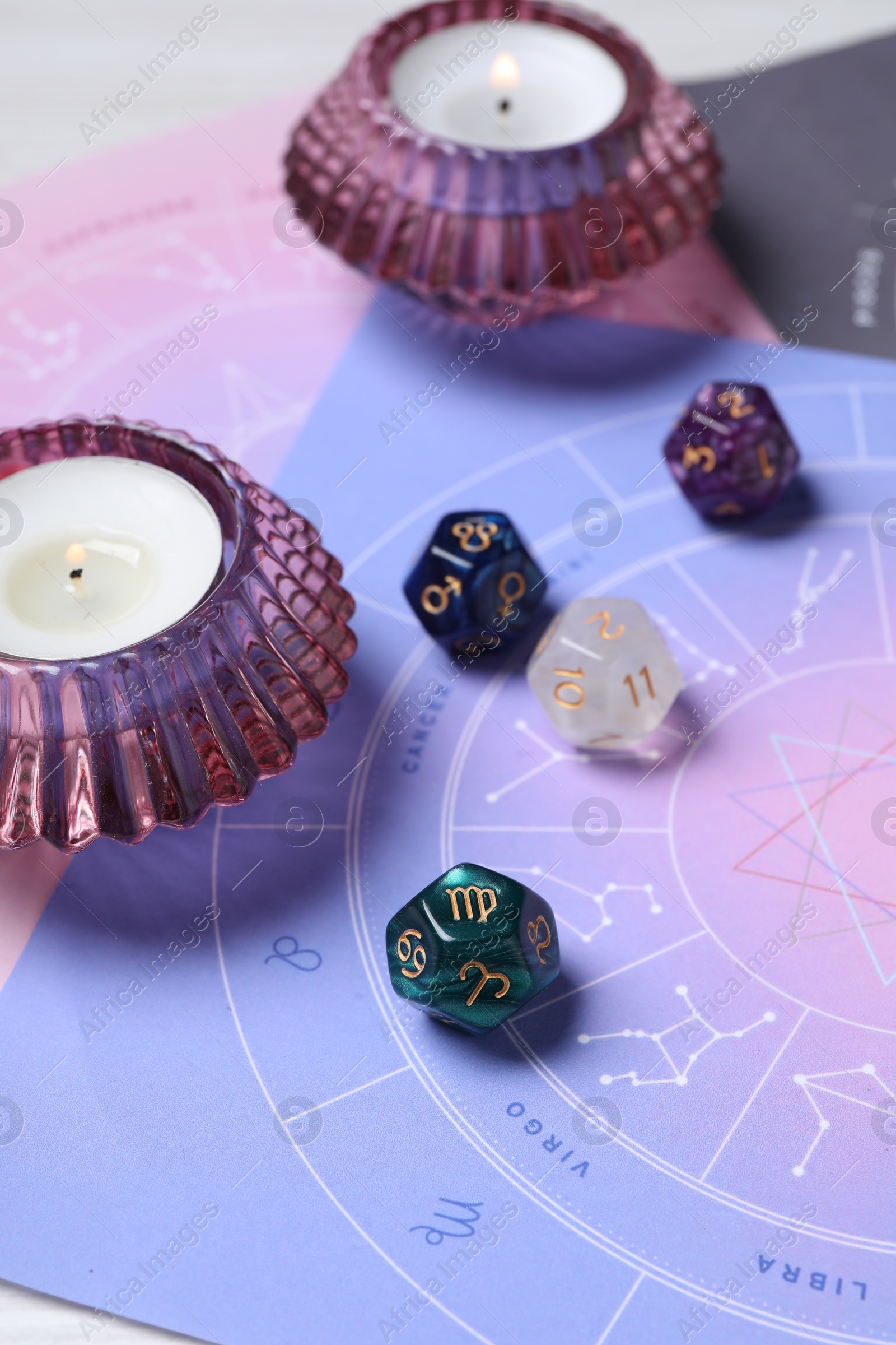 Photo of Zodiac wheels, astrology dices and burning candles on table, closeup